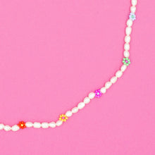 Load image into Gallery viewer, A handcrafted pearl necklace featuring daisy motifs, made in collaboration with a female artisan from Turkey. The pearls are natural and unique in shape, size, and color. The necklace is presented with a small fabric sack for safe keeping. The tone is elegant and warm, highlighting craftsmanship and cultural authenticity.