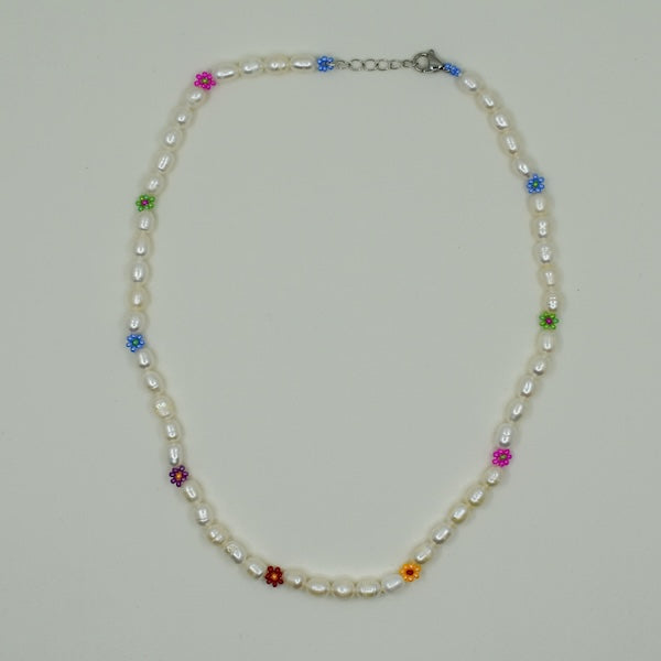 Eine handgefertigte Perlenkette mit Gänseblümchen-Motiven, gemeinsam mit einer türkischen Kunsthandwerkerin hergestellt. Die Perlen sind naturbelassen und variieren in Form, Größe und Farbe. Die Kette wird in einem kleinen Stoffbeutel zur Aufbewahrung geliefert. Der Ton ist elegant und herzlich und betont Handwerkskunst sowie kulturelle Authentizität.